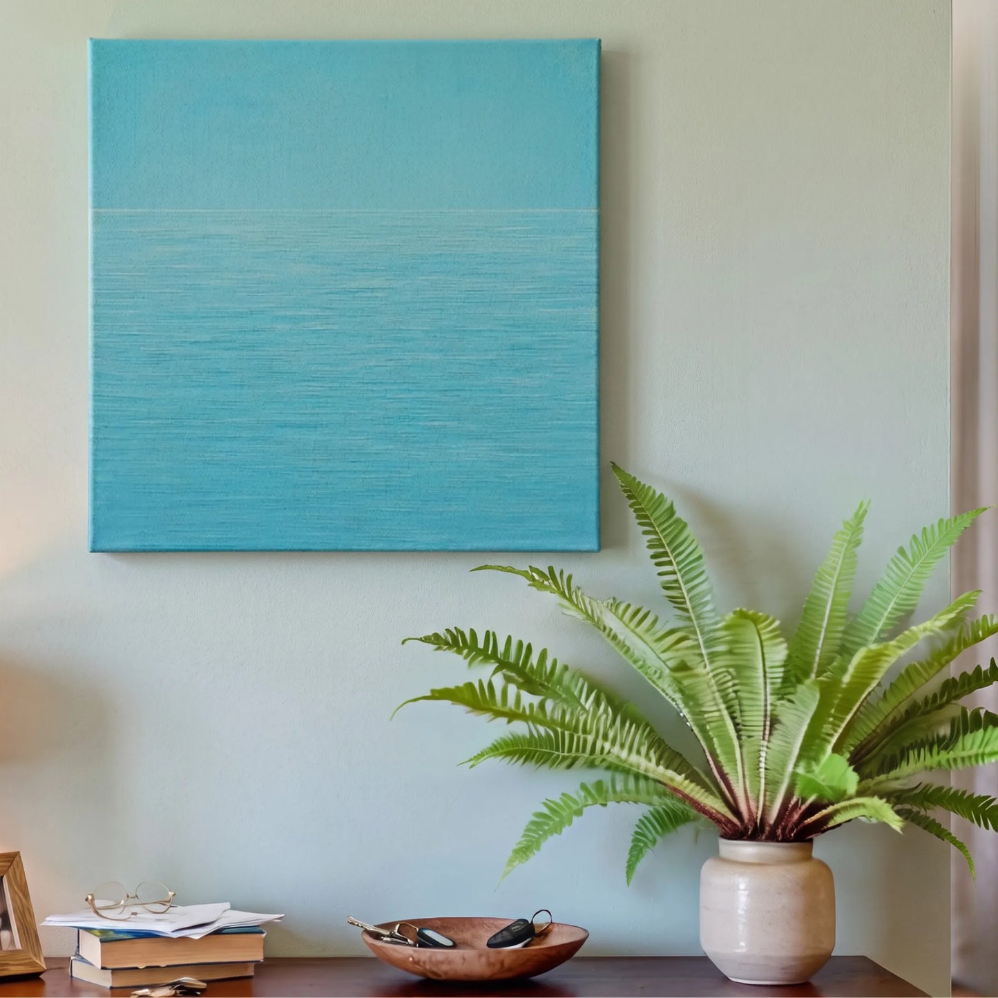 Navy blue wall art ocean canvas in entryway with white console table, potted plant, and warm downlighting